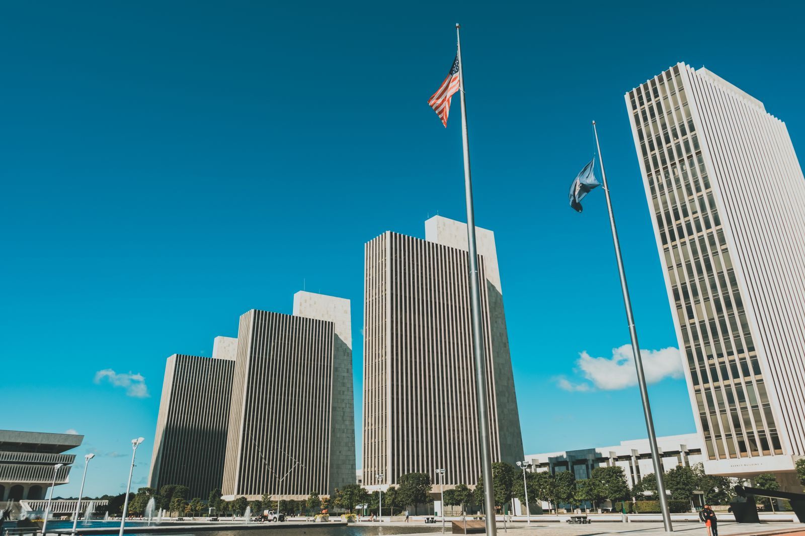 The marble office towers and flagpoles of the Empire State Plaza in Albany under a bright blue sky